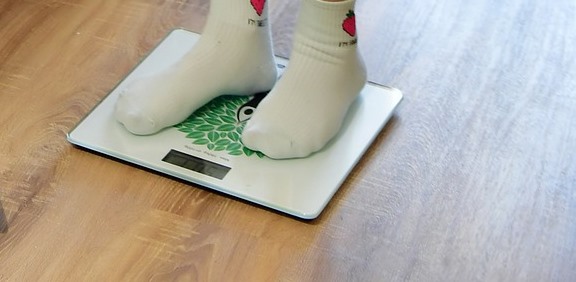 Person weighing themselves using bathroom scales.